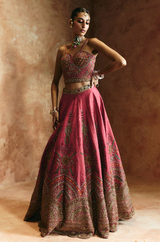 Full-length view with hand on hip showing the carrot pink blouse and embroidered lehenga panels by Aman Takyar at Mrs. G