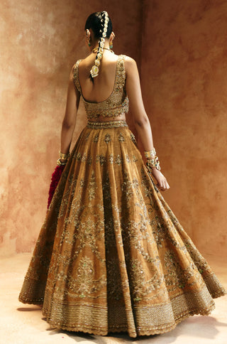 Back view of the copper gold lehenga set showing the scooped blouse back and flared skirt by Aman Takyar at Mrs. G