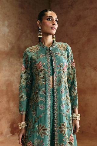 Waist-up view of the coral blue jacket's leaf and blossom embroidery and stand collar by Aman Takyar at Mrs. G