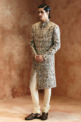 Full-length view of the dull green sherwani set with hands clasped and embroidery down the front by Aman Takyar at Mrs. G