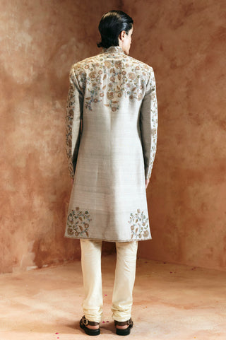Back view of the dull green sherwani with the floral yoke and hem panel by Aman Takyar at Mrs. G