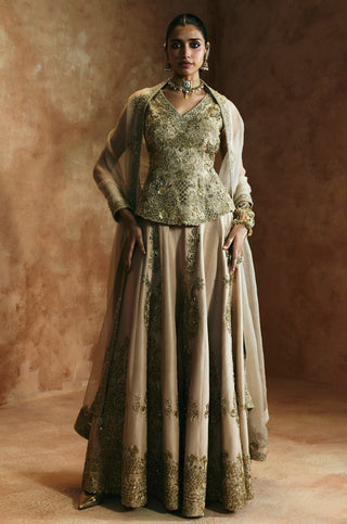 Full-length front view of the gold sharara set with the peplum top and sheer dupatta draped over the arms by Aman Takyar at Mrs. G