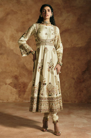 Front view of the ivory anarkali with a hand on the hip and embroidered bell sleeves by Aman Takyar at Mrs. G