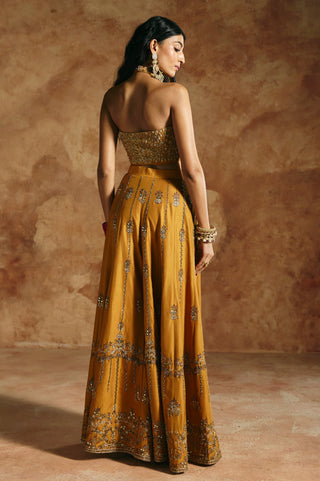 Back view of the mustard halter top's open back and the sharara's embroidered hem band by Aman Takyar at Mrs. G