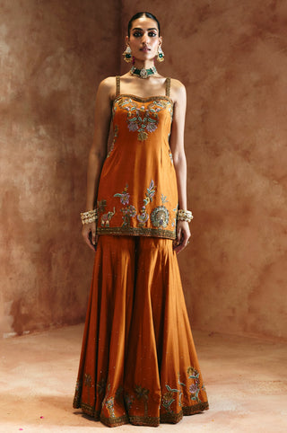 Full-length front view of the orange sharara set without the dupatta showing the flared sharara by Aman Takyar at Mrs. G