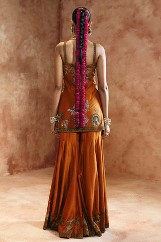 Back view of the orange sharara set with slim straps and the embroidered hem of the kurta by Aman Takyar at Mrs. G