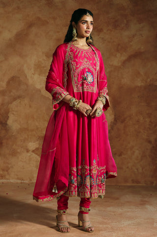 Three-quarter view of the fuchsia pink anarkali with embroidered cuffs and peacock hem band by Aman Takyar at Mrs. G