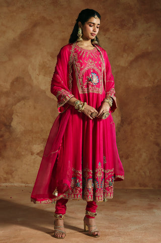 Side-turned view of the fuchsia pink anarkali's bell sleeve and the dupatta's tasseled corner by Aman Takyar at Mrs. G