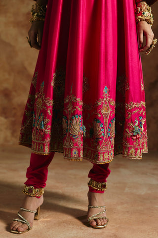 Close-up of the fuchsia pink anarkali's peacock and urn hem embroidery above the churidar by Aman Takyar at Mrs. G