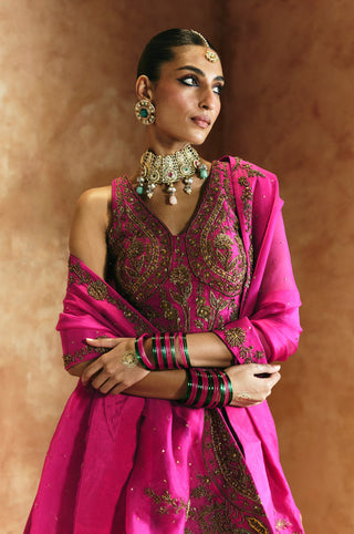 Waist-up side view of the rani pink blouse, tasseled dupatta corner and embroidered skirt by Aman Takyar at Mrs. G