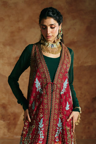 Waist-up close-up of the red jacket's pale blue leaf sprays, gold border and front tie by Aman Takyar at Mrs. G