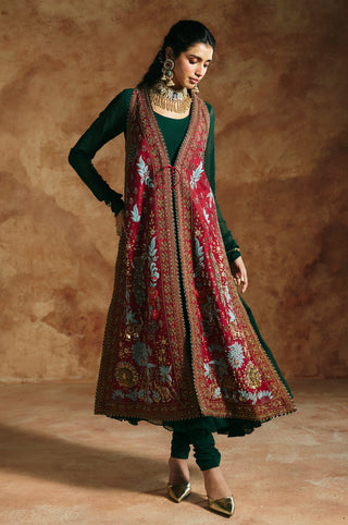 Full-length view with hand on hip showing the red jacket's embroidered hem and green anarkali by Aman Takyar at Mrs. G