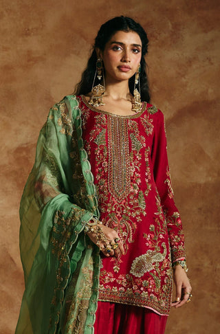 Front view of the red kurta set showing the embroidered hem and ankle cuffs of the salwar by Aman Takyar at Mrs. G