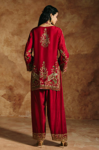 Back view of the red kurta with its embroidered center motif above the salwar hems by Aman Takyar at Mrs. G