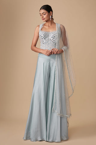 Full-length front view of the baby blue sleeveless mirror work corset blouse with plain flared sharara and net dupatta by Asaga at Mrs. G