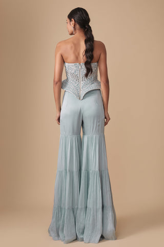 Full-length back view of the zip-back corset with pointed peplum hem above the tiered baby blue sharara by Asaga at Mrs. G