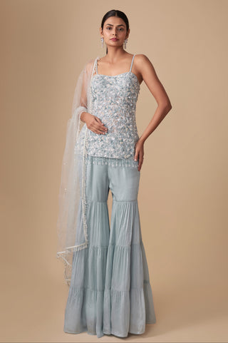 Full-length front view of the baby blue strappy floral kurti with tiered sharara and pearl-edged net dupatta by Asaga at Mrs. G