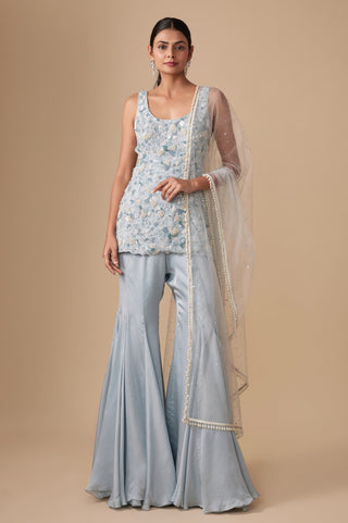 Full-length front view of the baby blue sleeveless floral short kurti with gored satin sharara and net dupatta by Asaga at Mrs. G