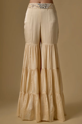 Detail of the beige three-tiered satin sharara with a mirror work waistband by Asaga at Mrs. G