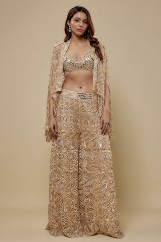 Front view of a beige mirror work blouse, sheer gold embroidered cape and wide-leg embroidered sharara by Asaga at Mrs. G