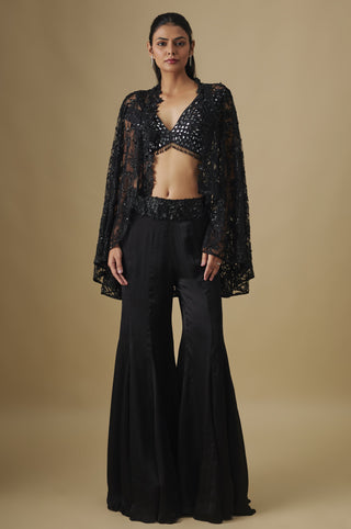 Front view of a black sharara set with a mirror blouse and a floral appliqué net cape by Asaga at Mrs. G
