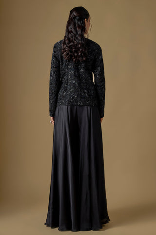 Back view of the black embroidered jacket with a curved hem over the flared sharara by Asaga at Mrs. G