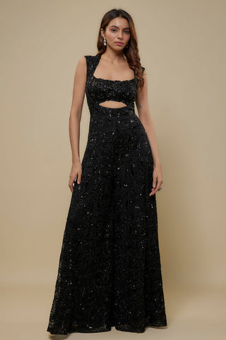 Front view of a black sleeveless wide-leg jumpsuit with abstract dori embroidery and a waist cutout by Asaga at Mrs. G