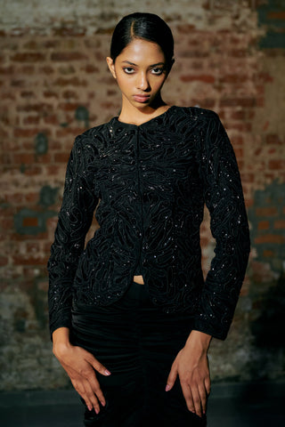 Waist-up view of the black round-neck jacket with swirling cord embroidery and sequins by Asaga at Mrs. G