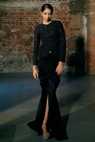 Front view of the black drape skirt's high slit and fishtail hem under the embroidered jacket by Asaga at Mrs. G