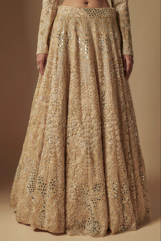 Waist-down view of champagne lehenga skirt with swirling gold motifs and mirror clusters by Asaga at Mrs. G