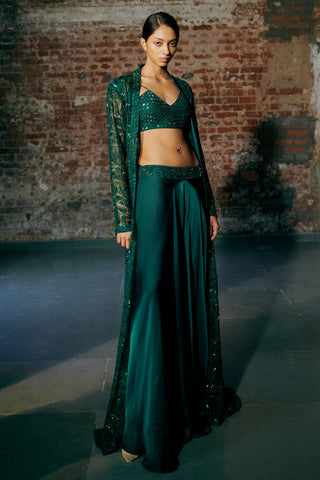 Three-quarter view of the emerald green jacket open over the blouse and satin sharara by Asaga at Mrs. G