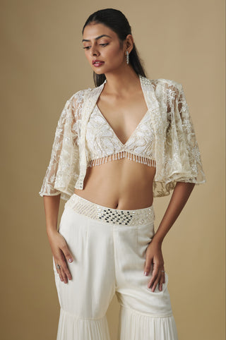 Waist-up view of the ivory V-neck blouse with a bead fringe under a floral net cape by Asaga at Mrs. G