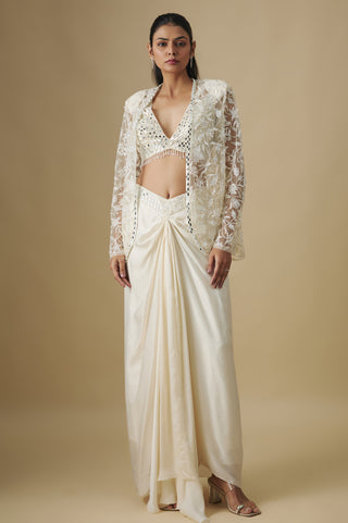Front view of an ivory floral net cape over a mirror blouse and a knot-drape satin skirt by Asaga at Mrs. G