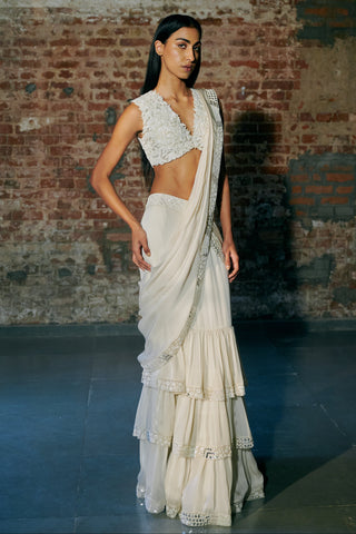 Front view of an ivory pre-draped saree with a leaf appliqué blouse and a three-tier ruffled skirt by Asaga at Mrs. G