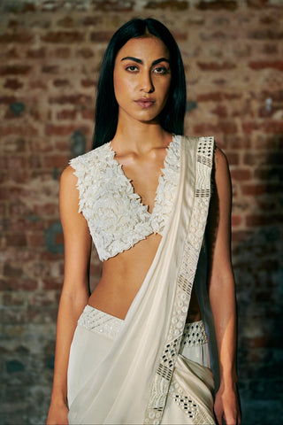 Waist-up view of the ivory V-neck blouse with raised leaf appliqué and a mirror-trimmed pallu by Asaga at Mrs. G