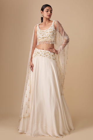 Full-length front view of the ivory gold fringe crop blouse and flowing satin lehenga with beaded net dupatta by Asaga at Mrs. G