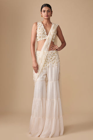 Full-length front view of the ivory gold floral appliqué blouse with the tiered sharara and net pallu draped over the shoulder by Asaga at Mrs. G