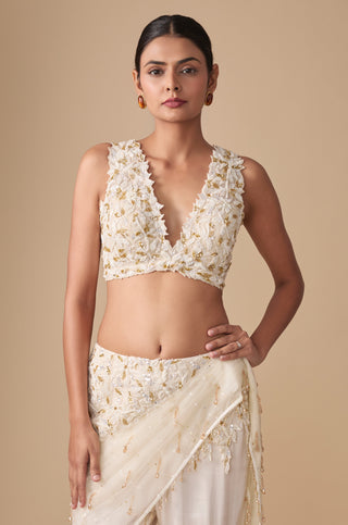 Waist-up view of the deep V-neck blouse in raised white petals and gold sequins with the embroidered waistband and net pallu by Asaga at Mrs. G