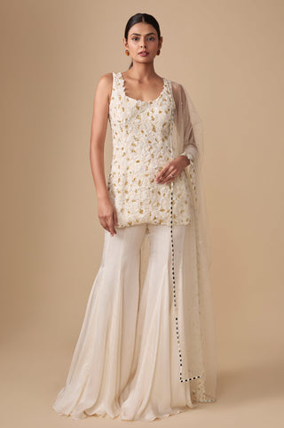 Full-length front view of the ivory gold sleeveless short kurti with flared sharara and net dupatta by Asaga at Mrs. G