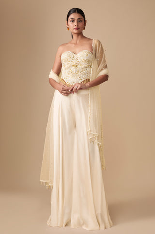 Full-length front view of the ivory gold strapless corset blouse with plain flared sharara and net dupatta by Asaga at Mrs. G
