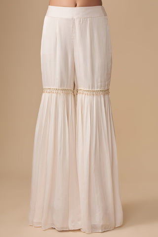 Close-up of the gathered ivory sharara with a beaded latkan band at the knee by Asaga at Mrs. G