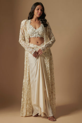 Front view of ivory moon pie floral appliqué blouse, knotted drape skirt and sheer long jacket by Asaga at Mrs. G