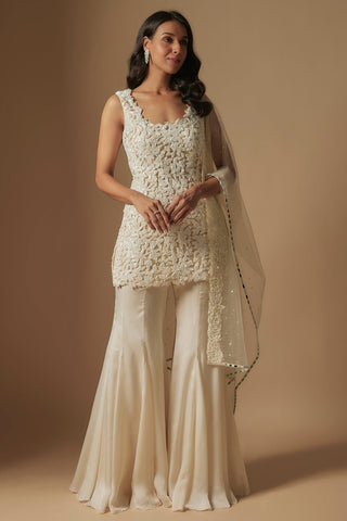 Front view of ivory tidal short kurti in leaf appliqué with flared sharara and net dupatta by Asaga at Mrs. G