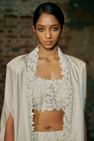 Waist-up view of the ivory square-neck corset with leaf appliqué and the cape edging by Asaga at Mrs. G