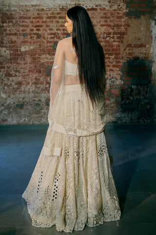 Back view of the ivory lehenga's flared skirt with the sheer dupatta draped from the shoulders by Asaga at Mrs. G