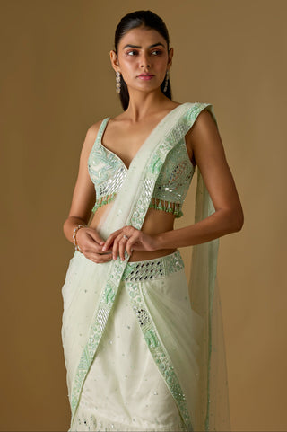 Three-quarter view of the mint pallu crossing one shoulder over the mirror work blouse and embroidered border by Asaga at Mrs. G