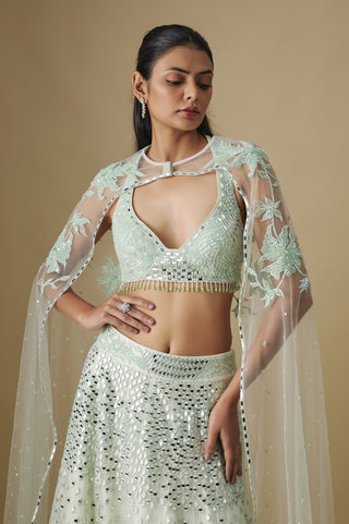 Waist-up view of the mint V-neck blouse with a gold bead fringe and the keyhole cape by Asaga at Mrs. G