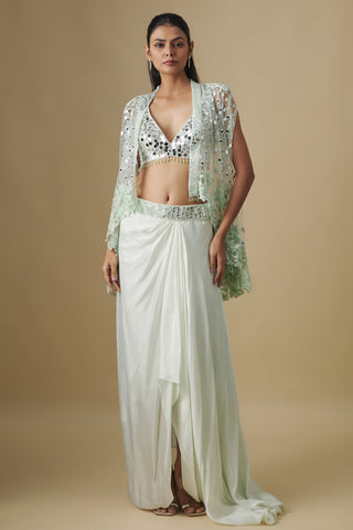 Full-length front view of a mint draped satin skirt with a mirror blouse and a floral appliqué net cape by Asaga at Mrs. G