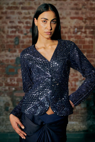 Waist-up view of the navy blue V-neck sequin and mirror jacket above the knotted drape by Asaga at Mrs. G