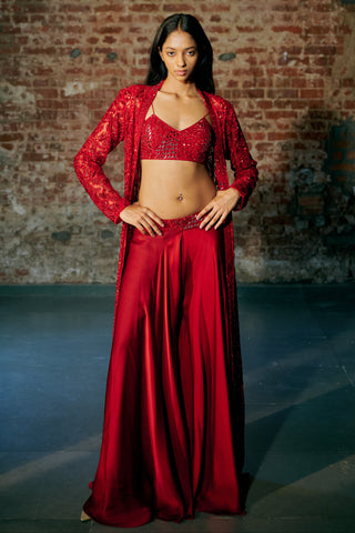 Front view of the red long jacket with hands on hips over the sequin blouse and wide sharara by Asaga at Mrs. G